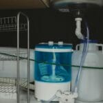 Mała pralka turystyczna podłączona do instalacji w schowku