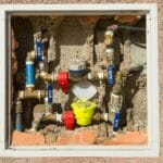 Złożony zestaw wodomierzy zamontowany w ścianie z betonu